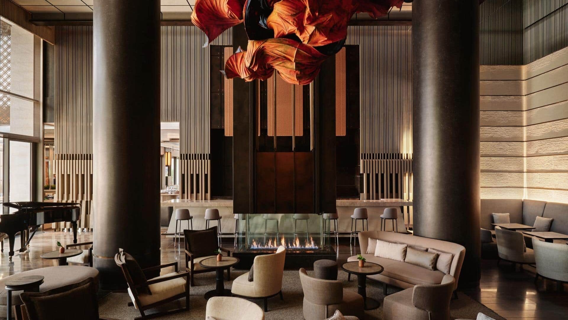 Aman New York suite living room with floor-to-ceiling windows, fireplace, and soft neutral furnishings overlooking the city