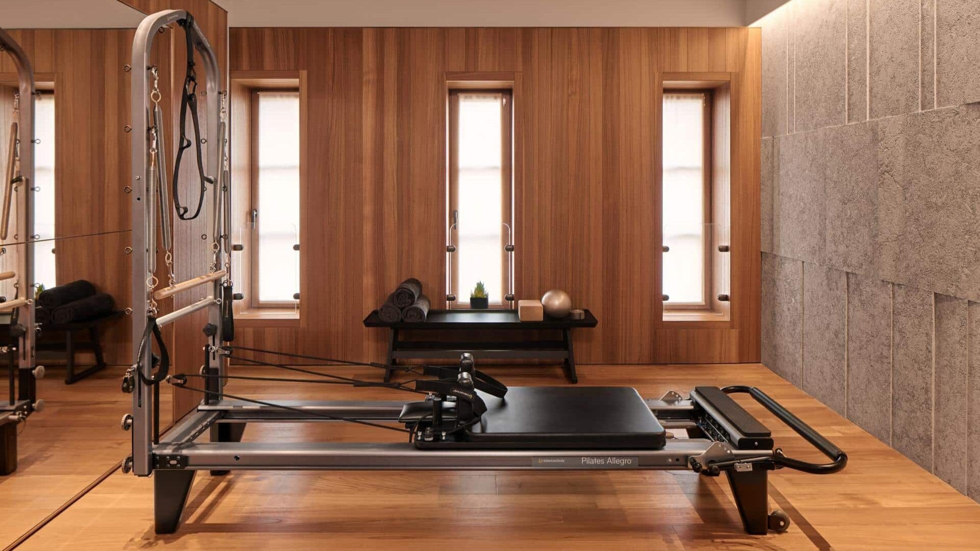Pilates studio at Bulgari Hotel Rome, featuring a reformer machine set within a warm, wood-panelled space with soft natural light and a calm, minimal design.