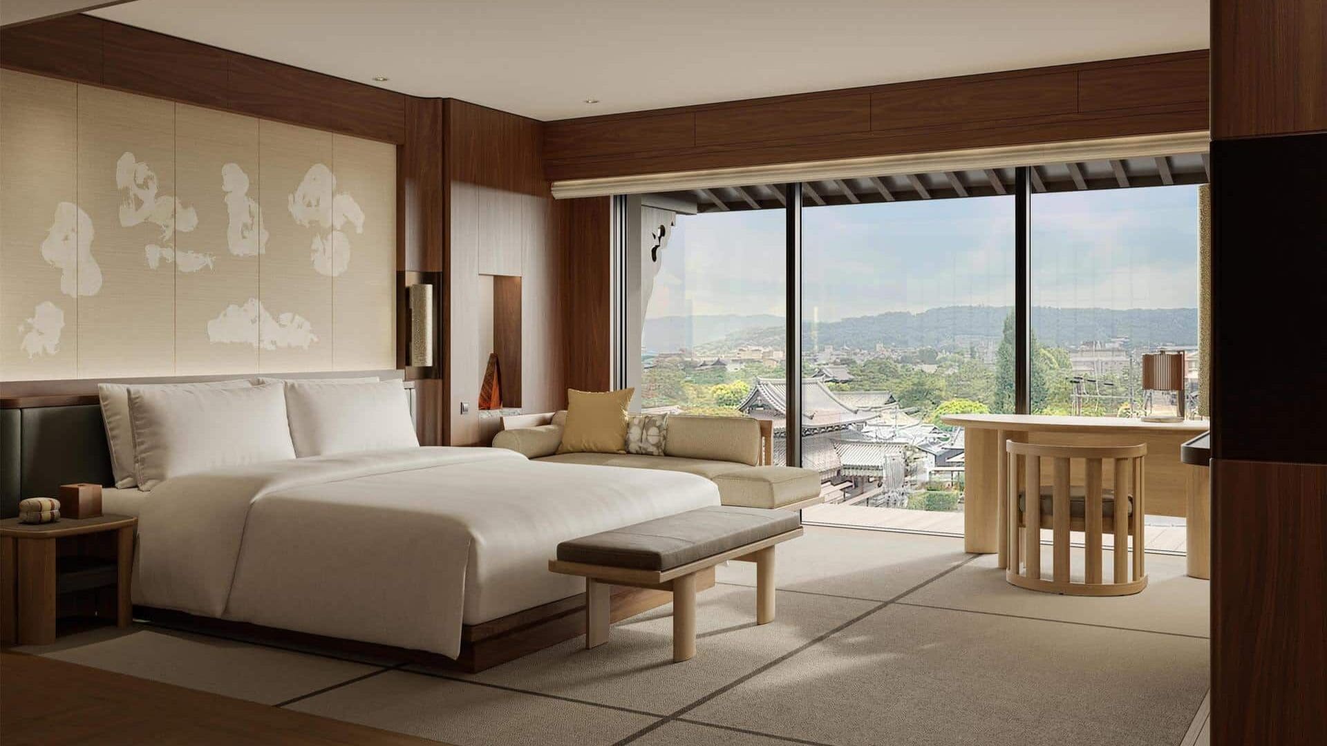 Capella Kyoto hotel room with tatami flooring, low bed, wood interiors, and balcony view over traditional Kyoto rooftops and hills
