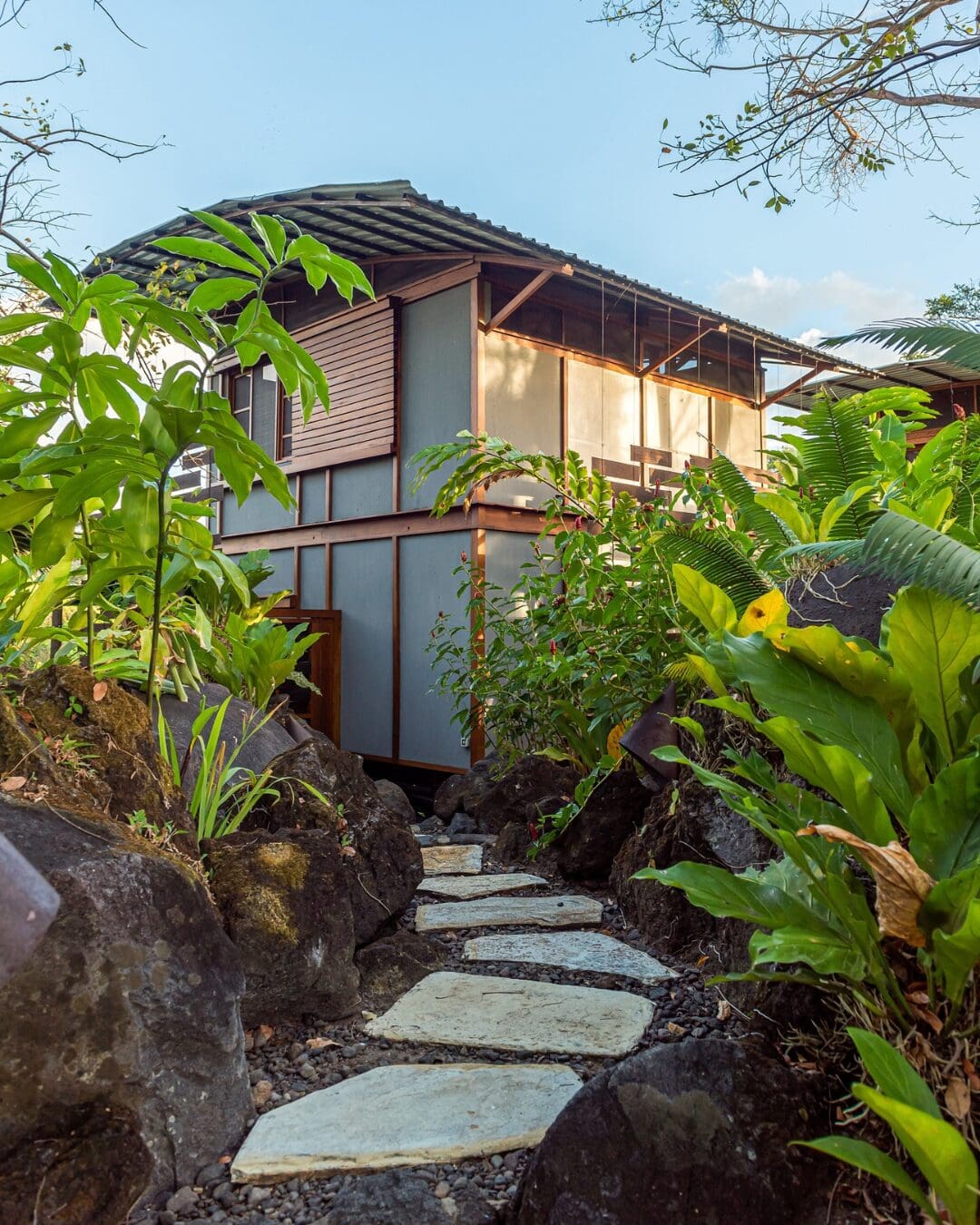 A wooden casita at Jicaro Private Island set among tropical plants, with a stone path leading through lush greenery.